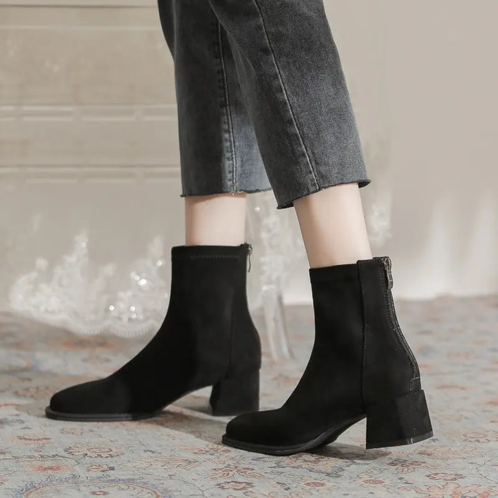 Zylos black suede-like ankle boots with a square toe and chunky block heel, worn with denim jeans. The boots feature a back zipper closure and mid-calf shaft.