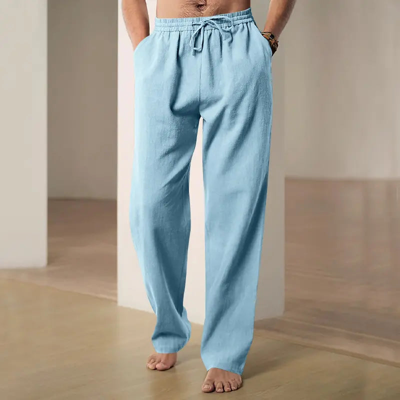 Man wearing light blue Zylos linen-blend wide-leg trousers with a drawstring waist and side pockets, shown in a casual, relaxed setting.