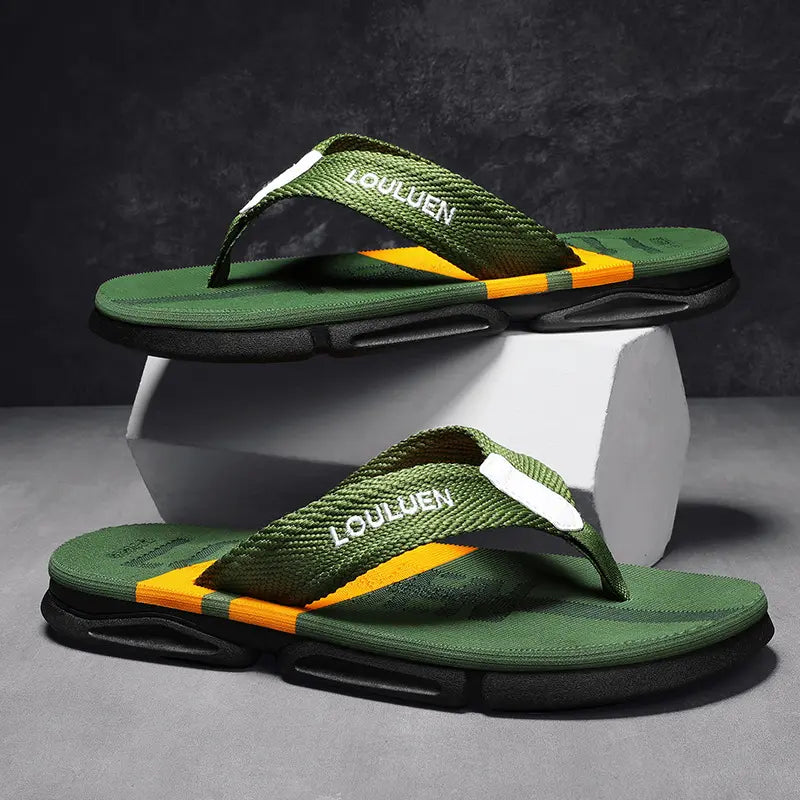 Men's green flip-flops with woven straps featuring an orange stripe and white 'LOULUEN' embroidery, resting on a multi-layered black and red sole against a dark textured background.