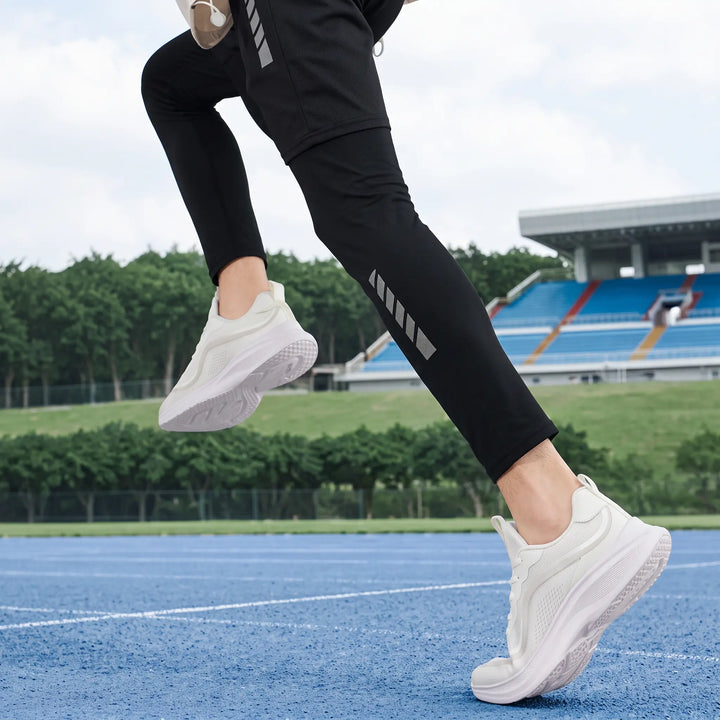 Person running on a blue track wearing white Zylos men&