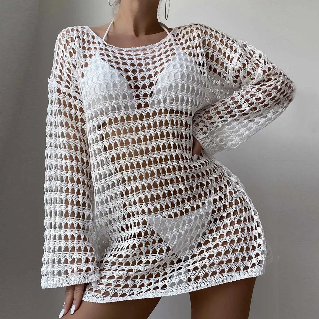 White Zylos crochet beach cover-up mini dress with long sleeves and open knit pattern, worn by a model over swimwear.
