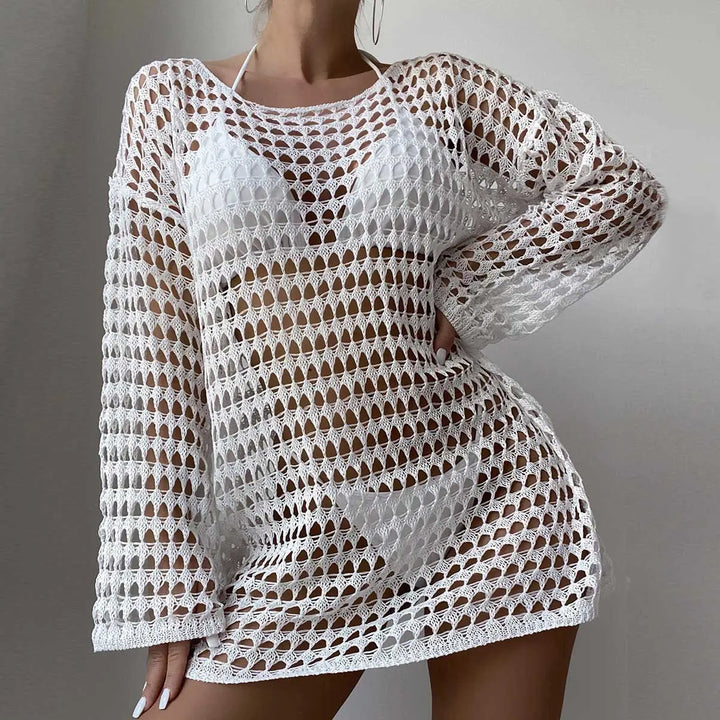 White Zylos crochet beach cover-up mini dress with long sleeves and open knit pattern, worn by a model over swimwear.