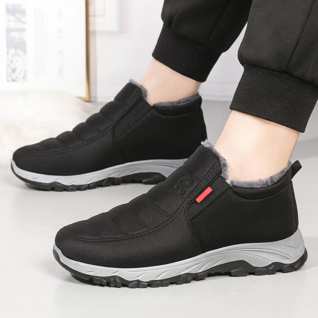 Black Zylpha winter boots with a quilted upper and grey faux-fur lining, shown on feet wearing jogger pants, offering warmth and comfort.
