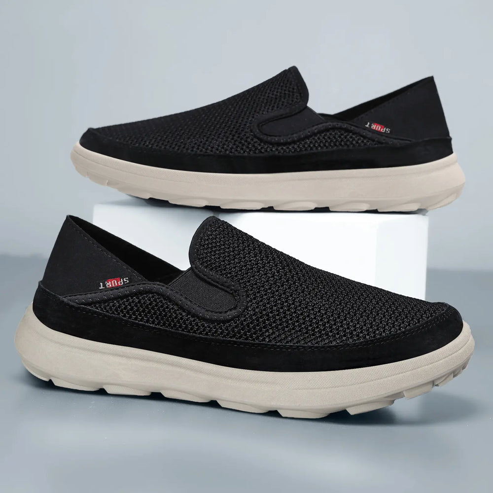 Black men's slip-on sneakers with breathable mesh upper, contrasting beige sole, and subtle 'SPORT' branding tag on the side.