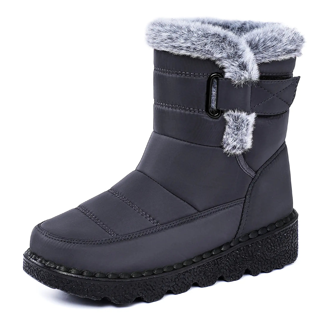 A pair of dark grey, mid-calf winter boots featuring a water-resistant quilted upper, plush faux fur lining around the cuff, a side zipper closure, and a thick, black lugged platform wedge sole. These warm snow boots offer comfort and style for winter.