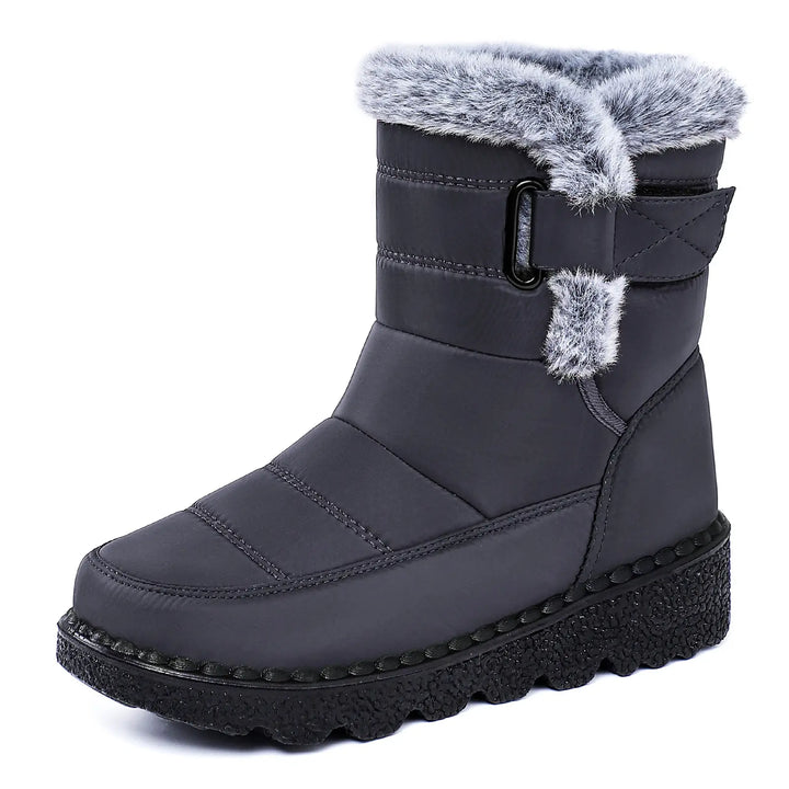 A pair of dark grey, mid-calf winter boots featuring a water-resistant quilted upper, plush faux fur lining around the cuff, a side zipper closure, and a thick, black lugged platform wedge sole. These warm snow boots offer comfort and style for winter.