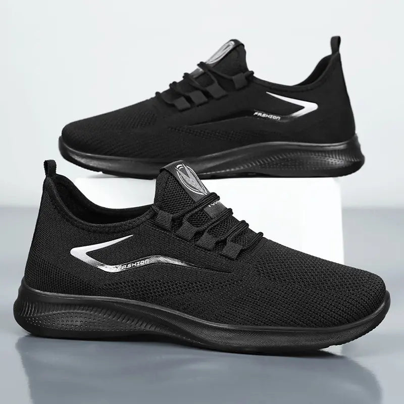 Pair of Zythos men's black breathable knit trainers shown from a three-quarter angle on a studio background, featuring a reflective 'FASHION' accent and a matte black sole.