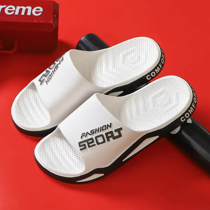 Zytri white comfort slides for men featuring a wide black 'Fashion Sport' strap and a contoured footbed, shown from a three-quarter angle on a red studio background.